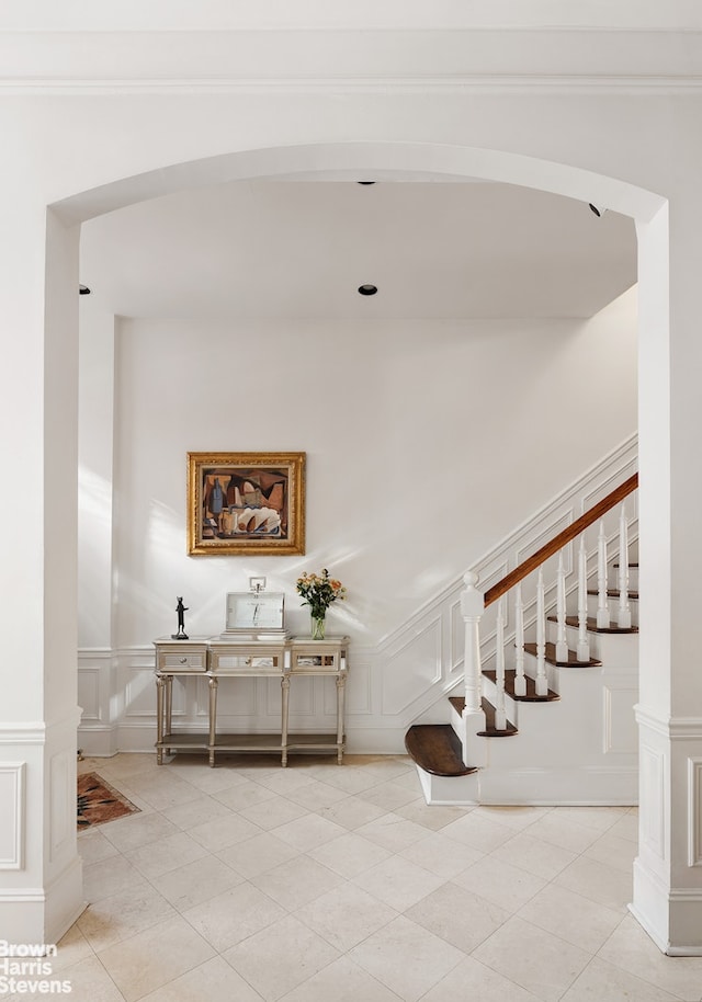 stairway with wainscoting, a decorative wall, and tile patterned floors