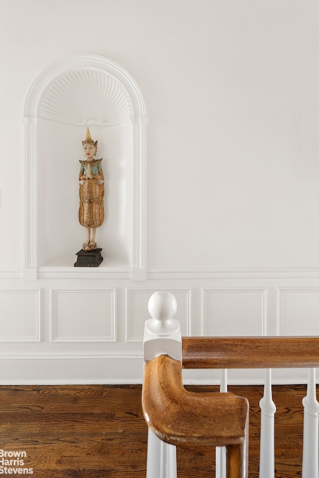 details featuring a decorative wall, a wainscoted wall, and wood finished floors
