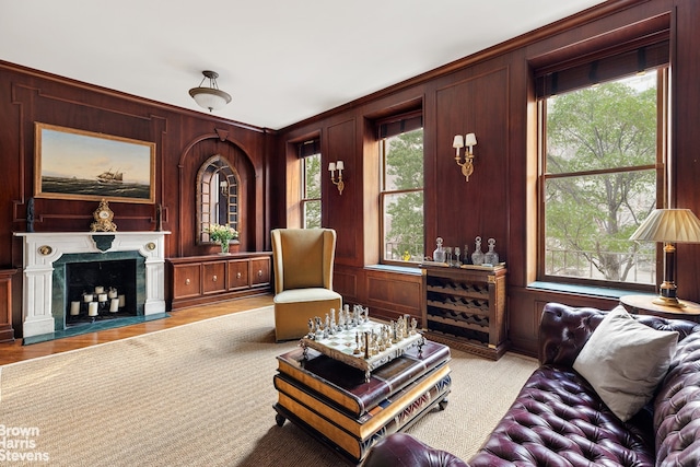 living room featuring a healthy amount of sunlight, wooden walls, and a premium fireplace