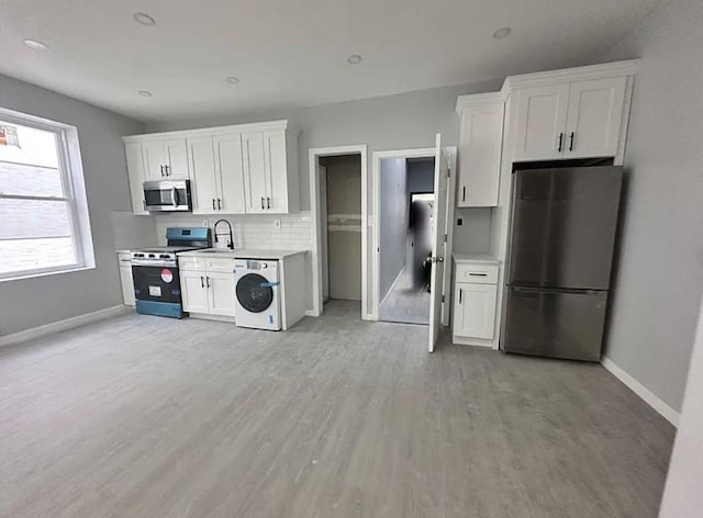 kitchen featuring washer / dryer, appliances with stainless steel finishes, and white cabinetry