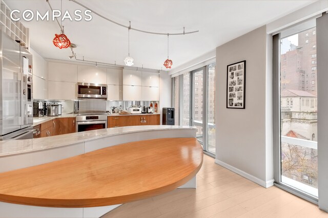 kitchen featuring decorative light fixtures, white cabinets, wall oven, and a healthy amount of sunlight