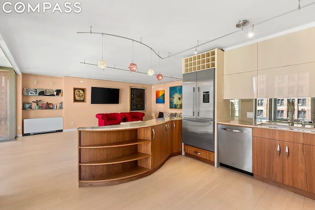 kitchen featuring rail lighting, sink, kitchen peninsula, stainless steel appliances, and light hardwood / wood-style floors