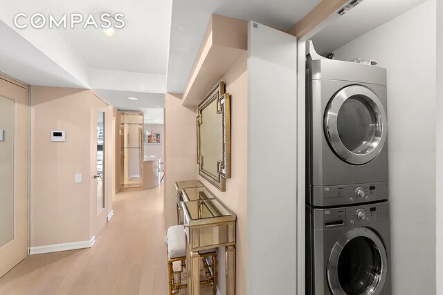 laundry area featuring stacked washing maching and dryer and light hardwood / wood-style floors