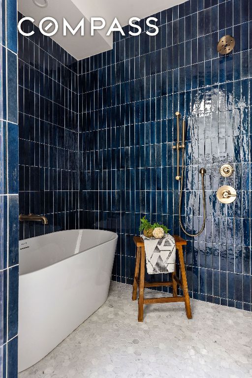 bathroom with tile walls, a shower, and a freestanding bath