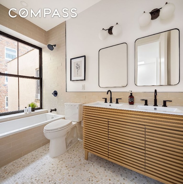 full bathroom with tiled shower / bath, a sink, tile walls, and toilet