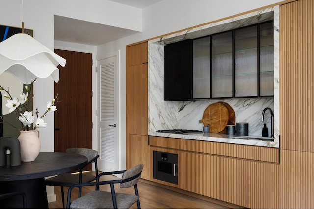 kitchen with a sink, backsplash, modern cabinets, and wood finished floors