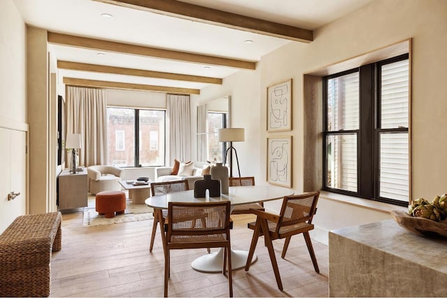 dining space with light hardwood / wood-style floors and beam ceiling