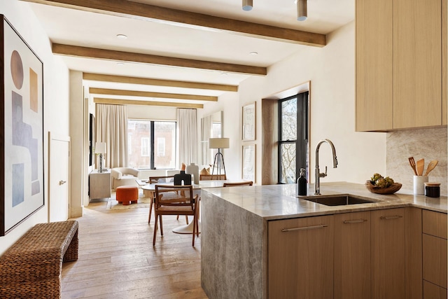 kitchen featuring a healthy amount of sunlight, light stone countertops, modern cabinets, and a sink