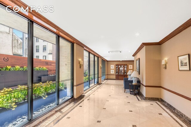 corridor with ornamental molding, marble finish floor, a healthy amount of sunlight, and baseboards