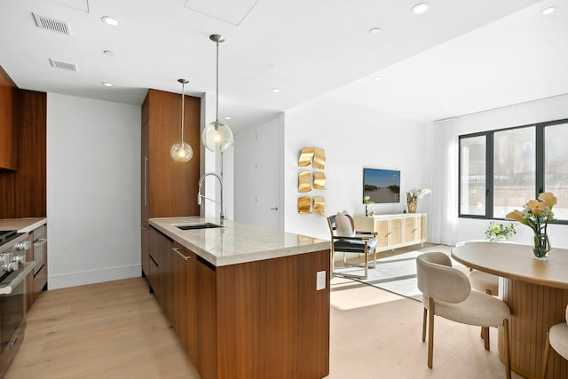 244 E 52nd St Unit 3C, New York City, NY 10022 - kitchen with a sink, modern cabinets, light wood-style flooring, brown cabinetry, and baseboards