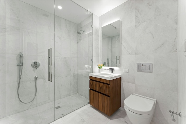 bathroom with toilet, vanity, tile walls, marble finish floor, and a shower stall