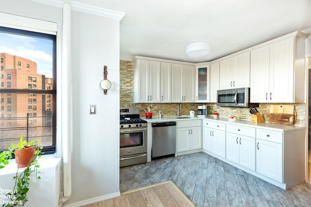 kitchen with backsplash, sink, stainless steel appliances, and white cabinetry