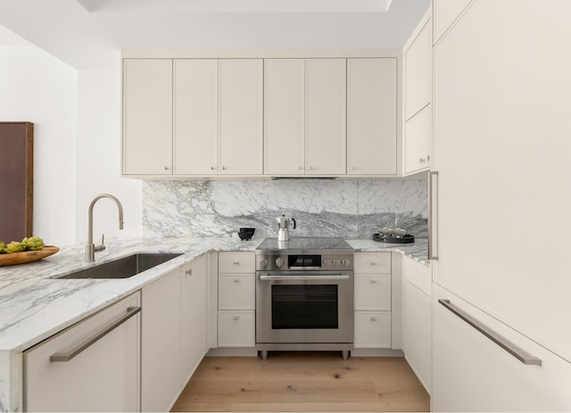 kitchen featuring light wood finished floors, stainless steel electric range, light stone countertops, and a sink