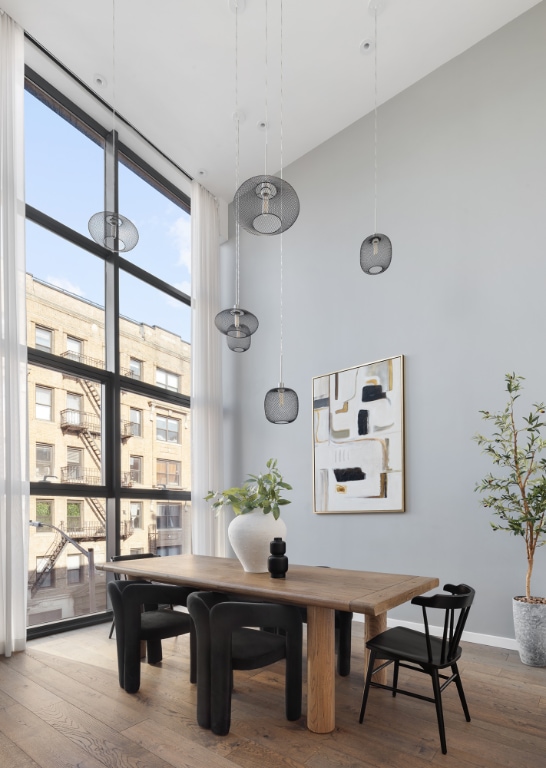 dining space featuring a high ceiling, hardwood / wood-style floors, and expansive windows