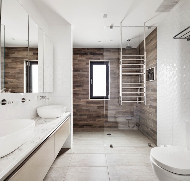 full bath with a sink, tile walls, and double vanity