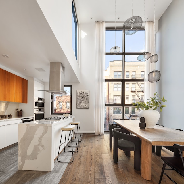 dining area featuring expansive windows, wood-type flooring, and a high ceiling