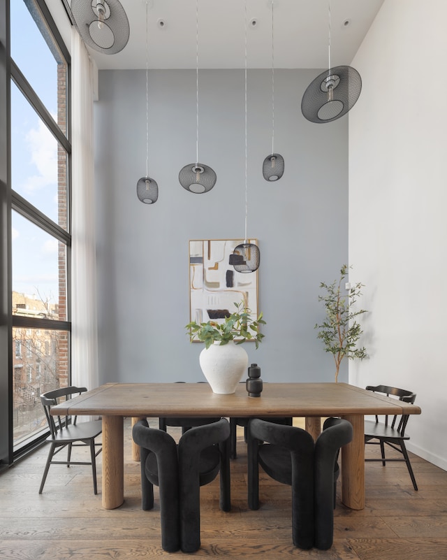 dining area featuring expansive windows, wood finished floors, and a towering ceiling