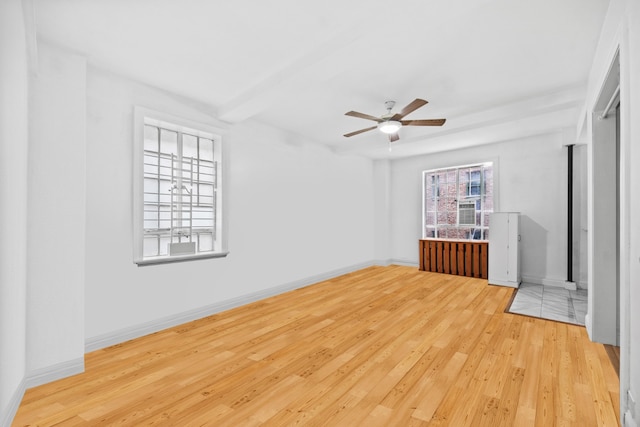 interior space with a ceiling fan, baseboards, and wood finished floors