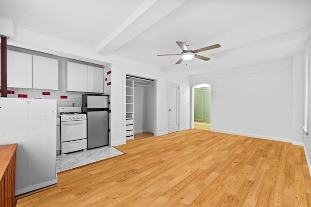 kitchen with white cabinetry, stainless steel fridge, white range with gas cooktop, ceiling fan, and beam ceiling