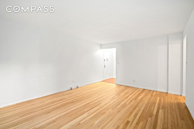 spare room featuring light wood-style floors and baseboards