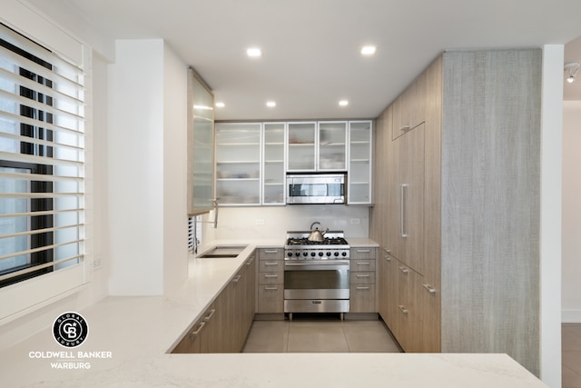 kitchen featuring sink, light stone countertops, appliances with stainless steel finishes, light brown cabinets, and light tile patterned floors