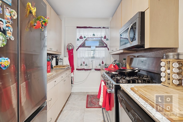 kitchen featuring light tile patterned floors, appliances with stainless steel finishes, light countertops, white cabinetry, and backsplash