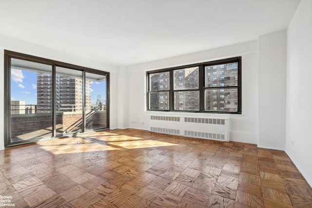 spare room featuring radiator, a city view, and baseboards