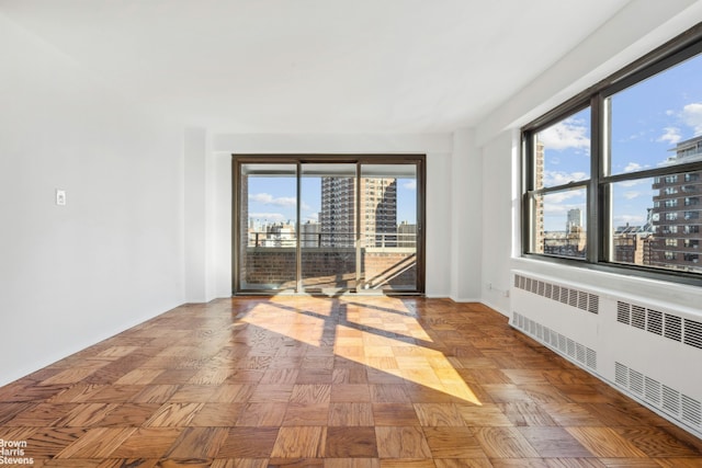 unfurnished room with a view of city and radiator heating unit