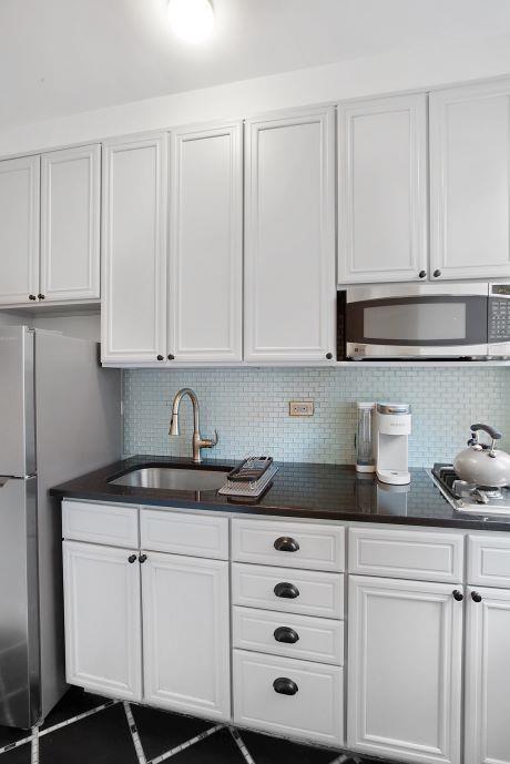 kitchen with white cabinets, decorative backsplash, and stainless steel appliances