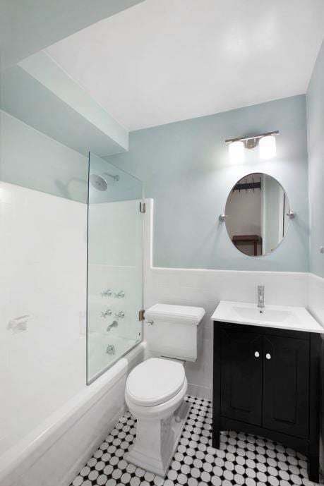 10 Park Ave Unit 2-C, New York City, NY 10016 - bathroom featuring vanity, combined bath / shower with glass door, tile patterned flooring, and wainscoting