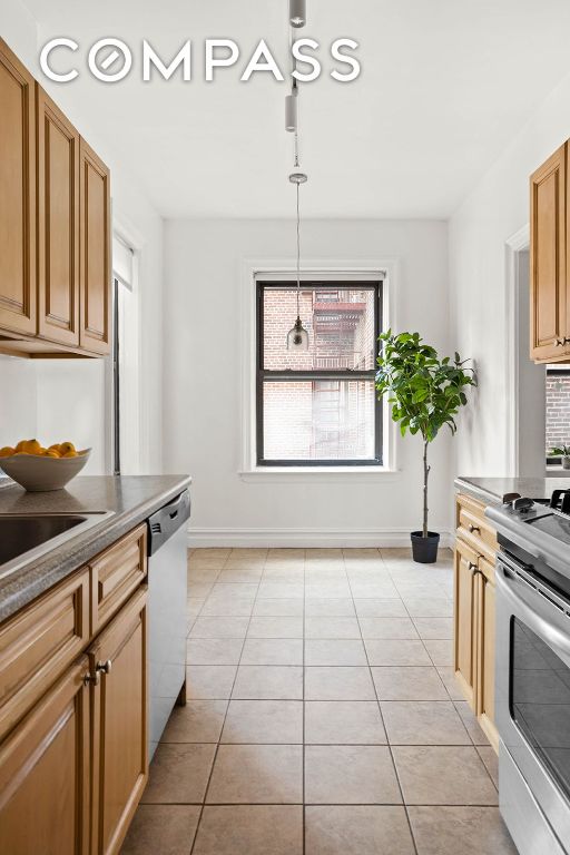 kitchen featuring stainless steel appliances, pendant lighting, light tile patterned flooring, and baseboards