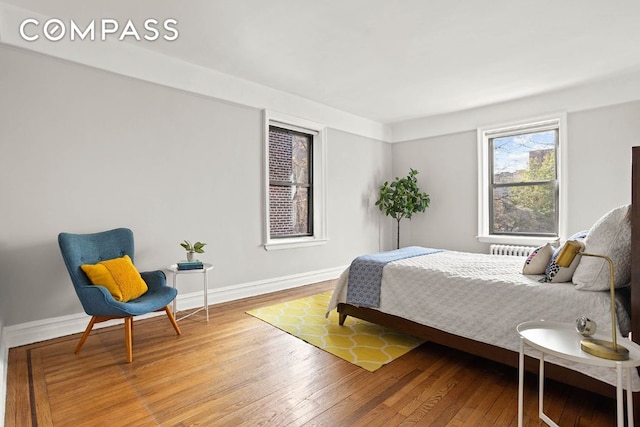 bedroom with radiator, baseboards, and wood finished floors