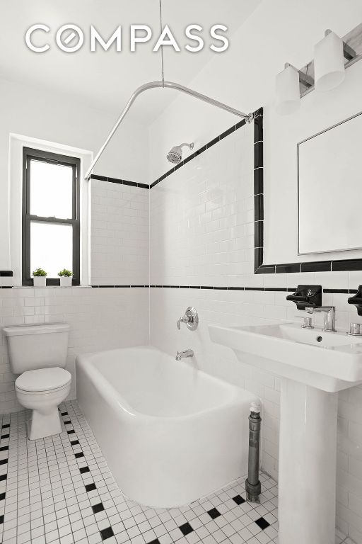 full bath with toilet, a sink, tile walls, and tile patterned floors