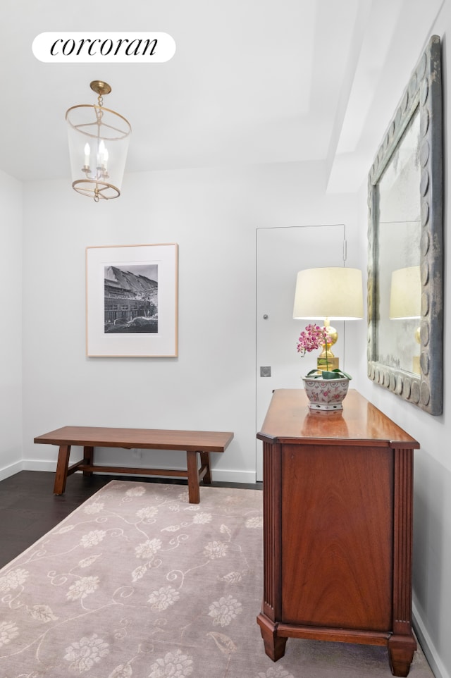 hall with a chandelier, wood finished floors, and baseboards