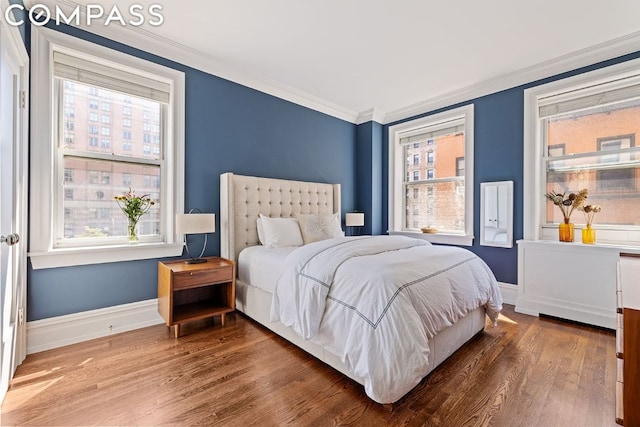 bedroom featuring hardwood / wood-style flooring, ornamental molding, and multiple windows