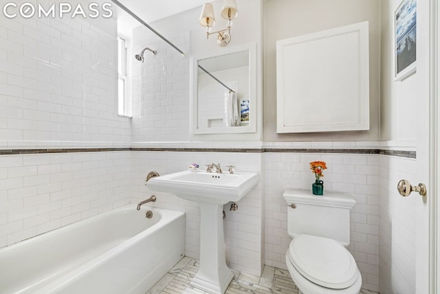 full bathroom with tiled shower / bath, toilet, sink, and tile walls