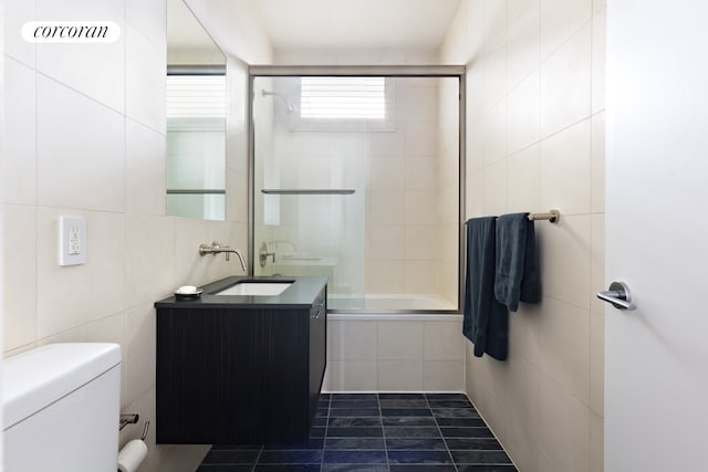 full bathroom featuring tile walls, toilet, tiled shower / bath combo, vanity, and tile patterned flooring