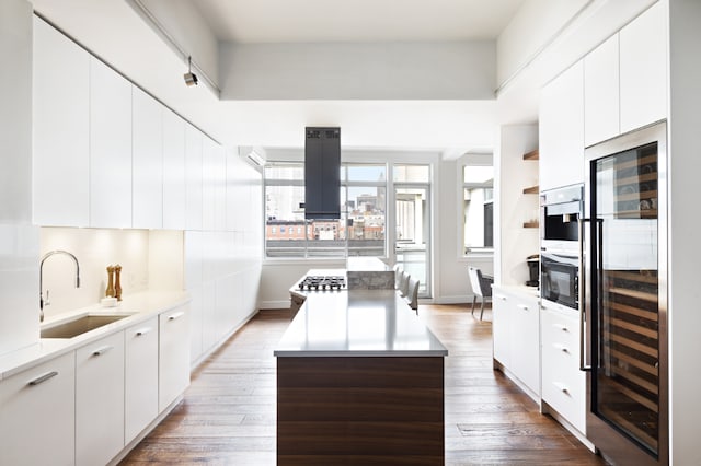 kitchen featuring a center island, light wood-style flooring, a sink, modern cabinets, and beverage cooler