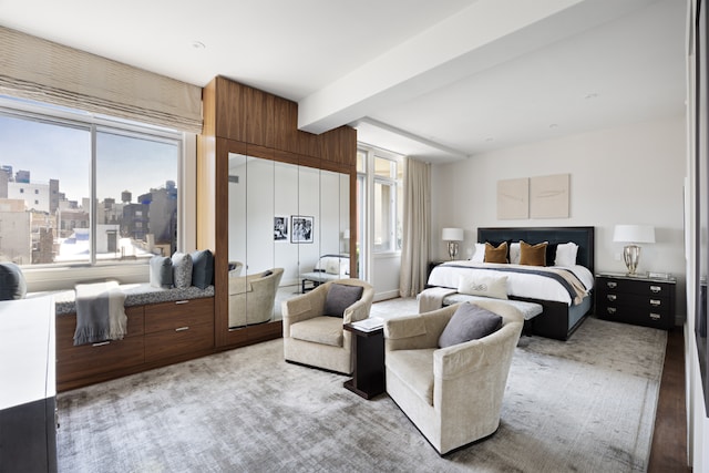 bedroom featuring beamed ceiling and a city view