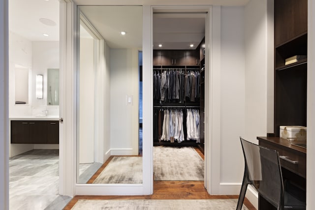 bathroom with a spacious closet, baseboards, wood finished floors, and vanity