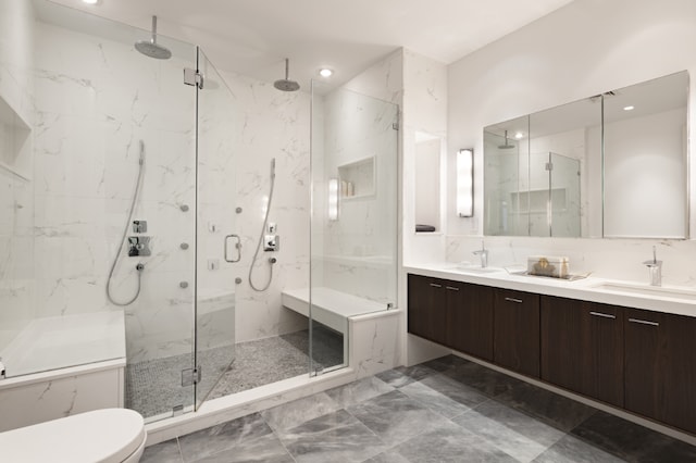 bathroom with toilet, a sink, a marble finish shower, and double vanity