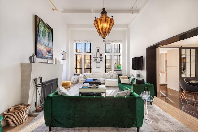 living room featuring a towering ceiling, beam ceiling, and hardwood / wood-style floors