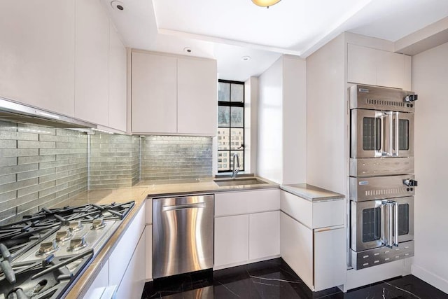 kitchen featuring tasteful backsplash, stainless steel appliances, sink, and white cabinets