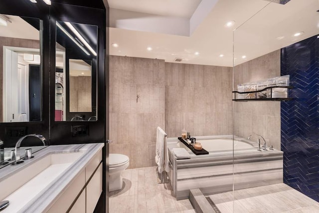 bathroom featuring tile walls, tile patterned flooring, vanity, tiled bath, and toilet