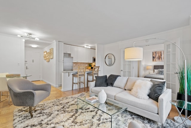 living room featuring light parquet floors, crown molding, and an inviting chandelier