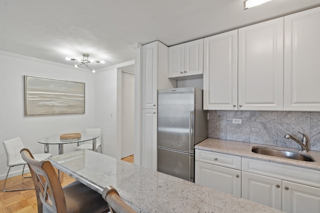 kitchen with white cabinets, sink, and stainless steel refrigerator