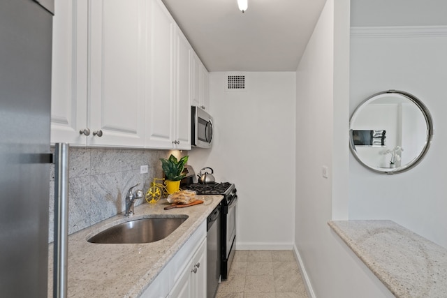 kitchen featuring light stone countertops, appliances with stainless steel finishes, white cabinetry, and sink