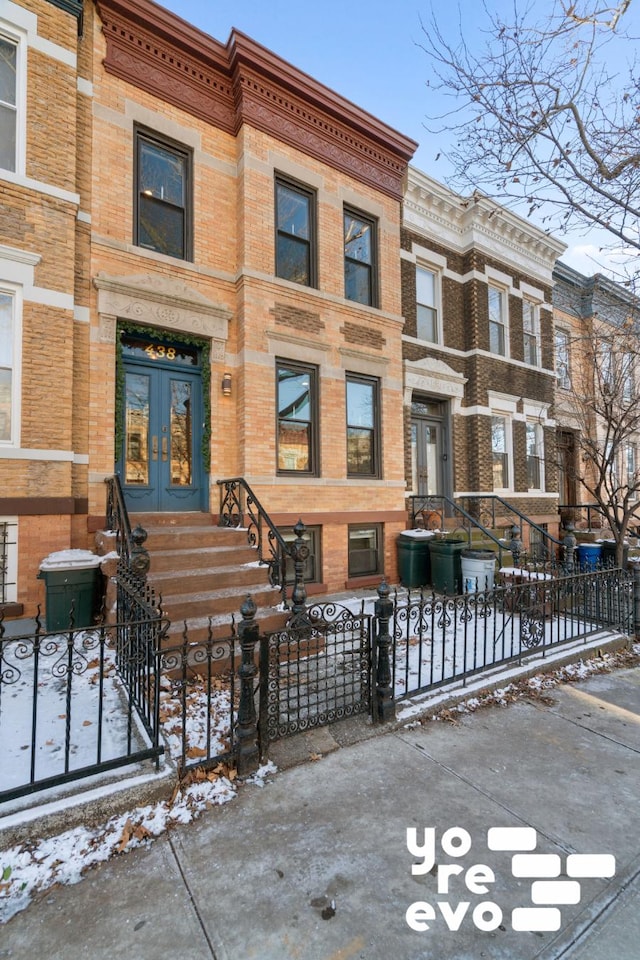 view of front of house featuring french doors, brick siding, and a fenced front yard