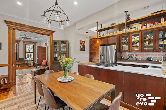 dining area with light wood-style floors, recessed lighting, ornamental molding, and an inviting chandelier