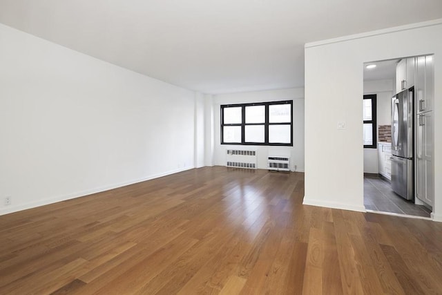 unfurnished room featuring radiator, light hardwood / wood-style floors, and an AC wall unit